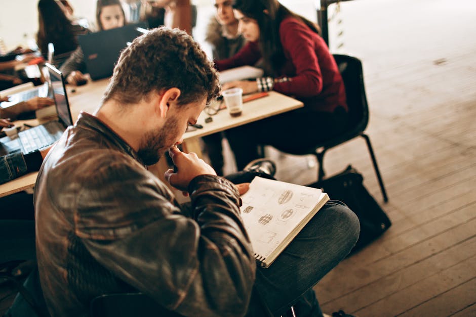A person smiling while learning on a laptop in a bright, modern cafe.